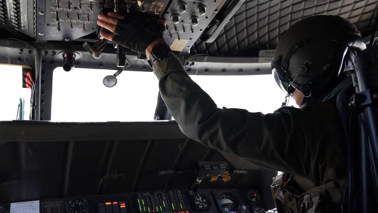 Helicopter pilot working overhead switches in a Blackhawk cockpit